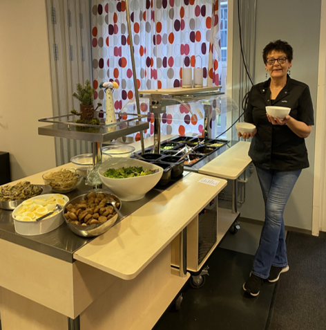 en person som står ved siden av et bord med mat på