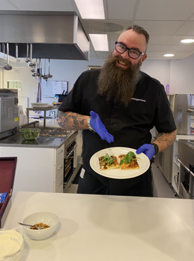 en person på et kjøkken med en tallerken mat