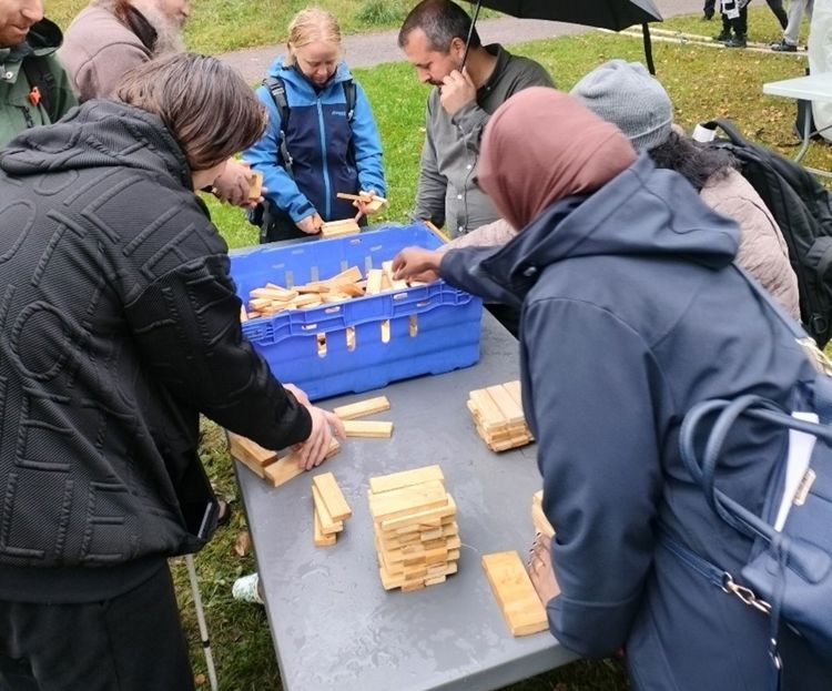 En gruppe mennesker bygger hus med treklosser.